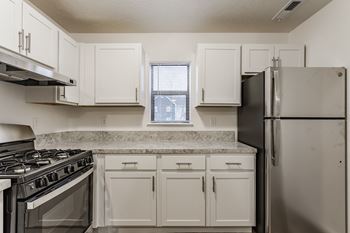 A kitchen with white cabinets and a black refrigerator.